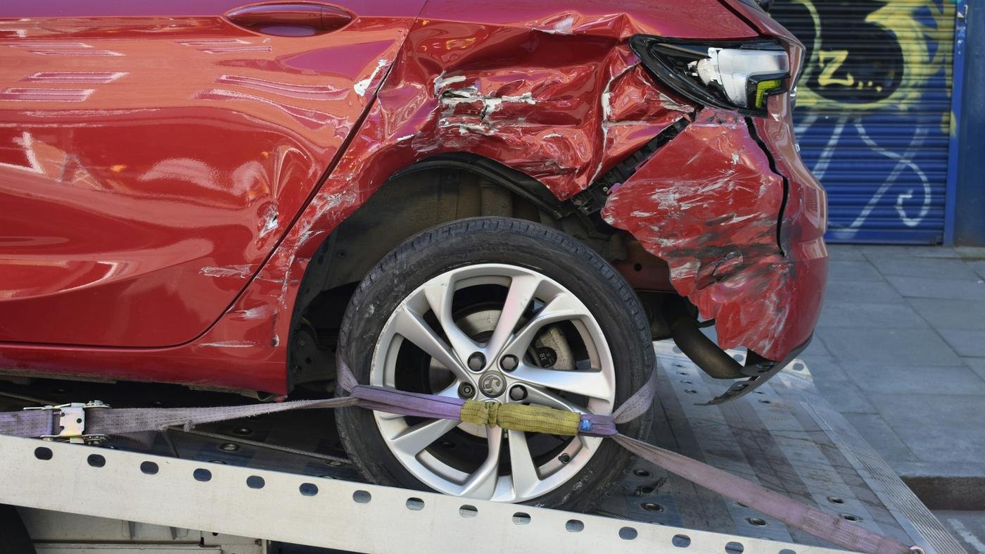 Damaged car being loaded onto a tow truck, representing what motor insurance covers